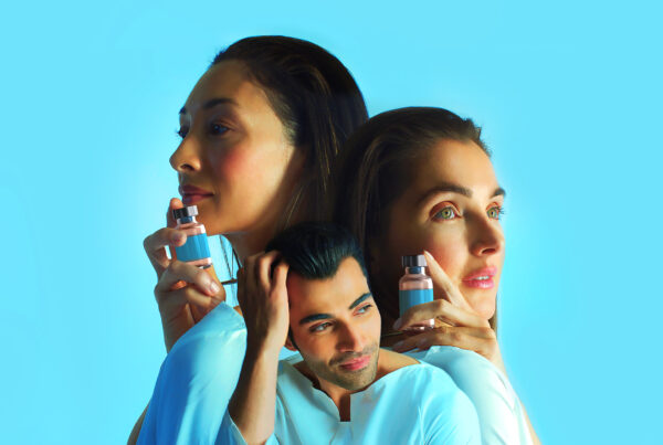 Three people holding skincare products against a bright blue background.